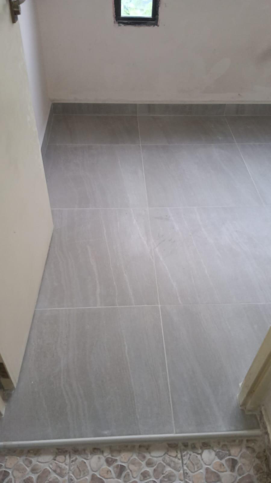 Finished grey floor tiling with new skirting