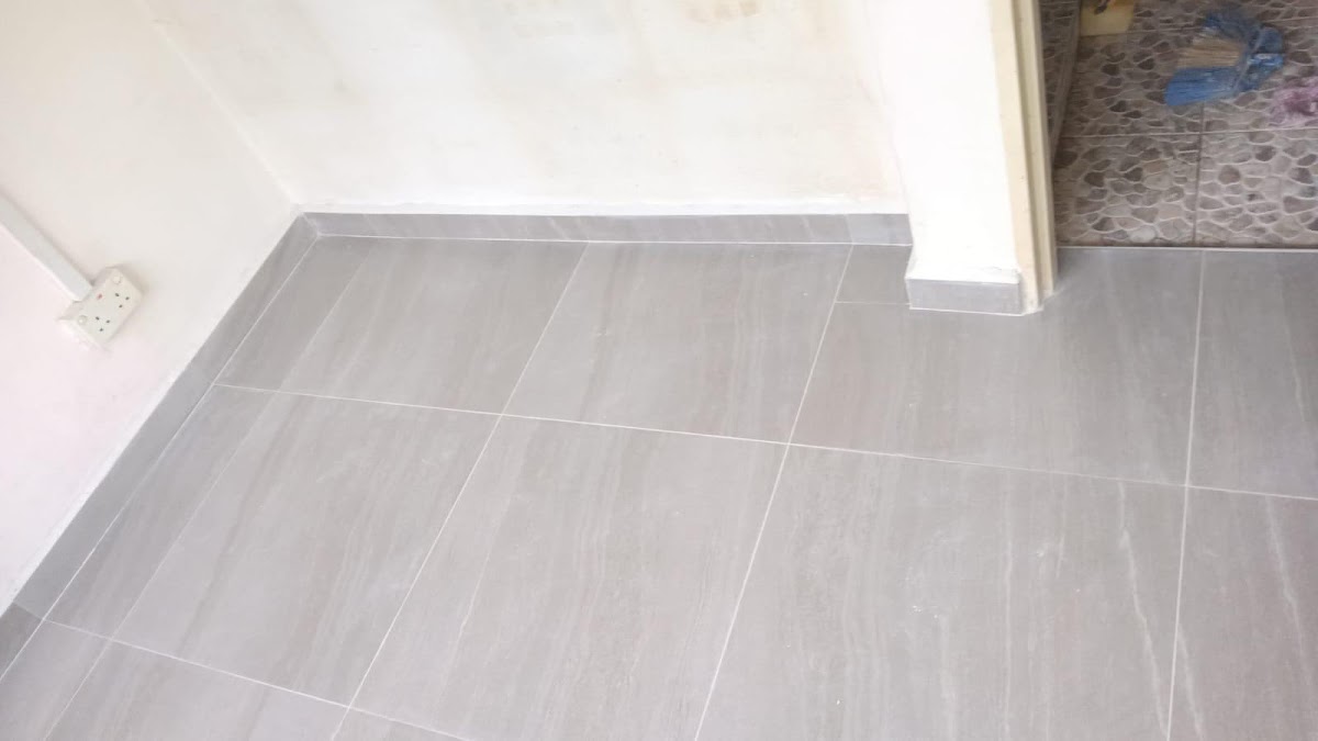 Finished grey floor tiling beside a wall socket